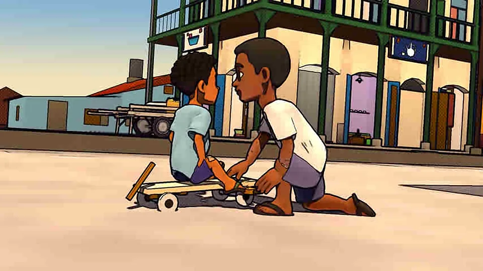 An older boy kneels beside a younger one on his board, showing him where to put his heel.